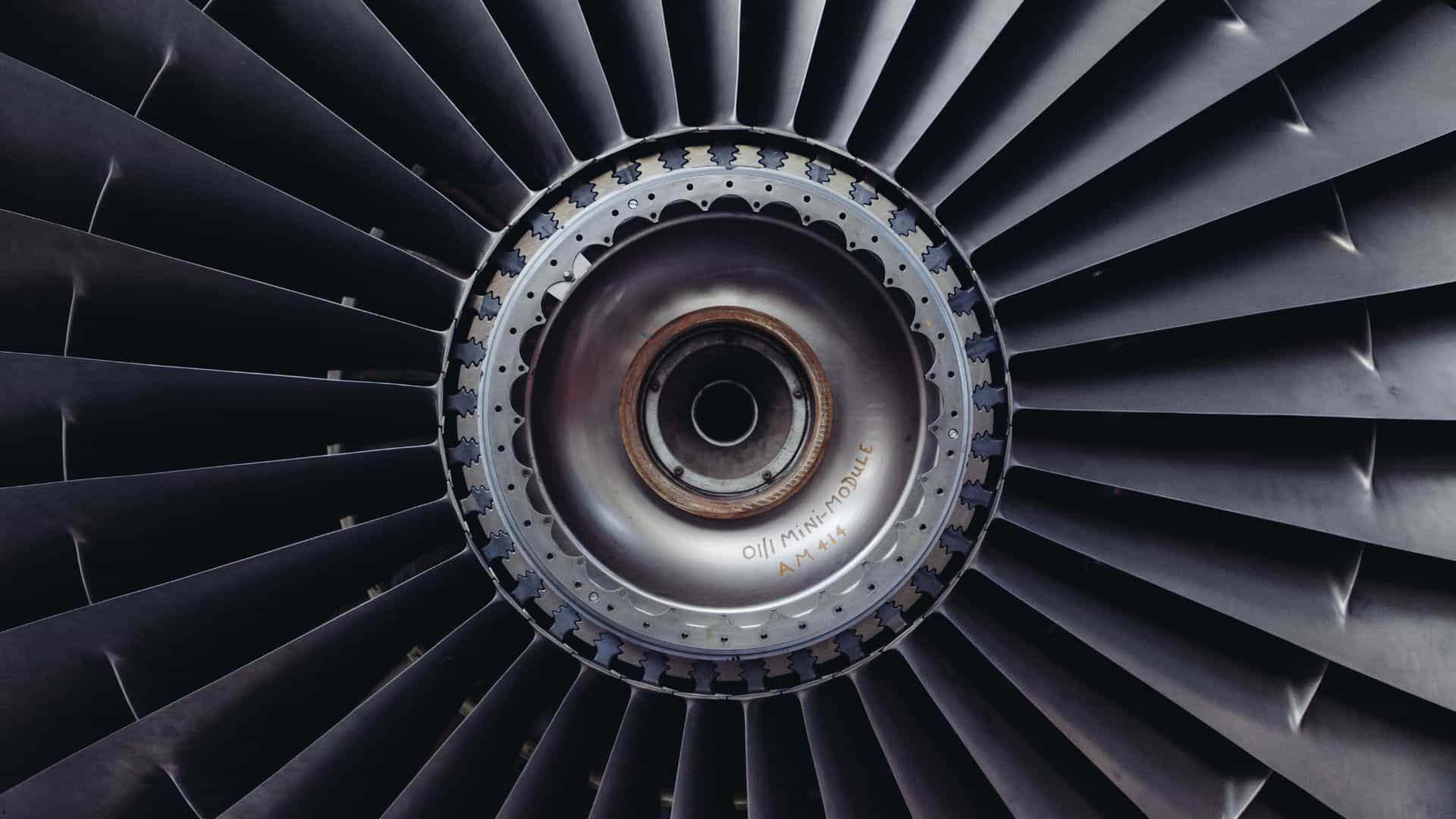Close-up of a jet engine fan with dark turbine blades radiating from the center hub.