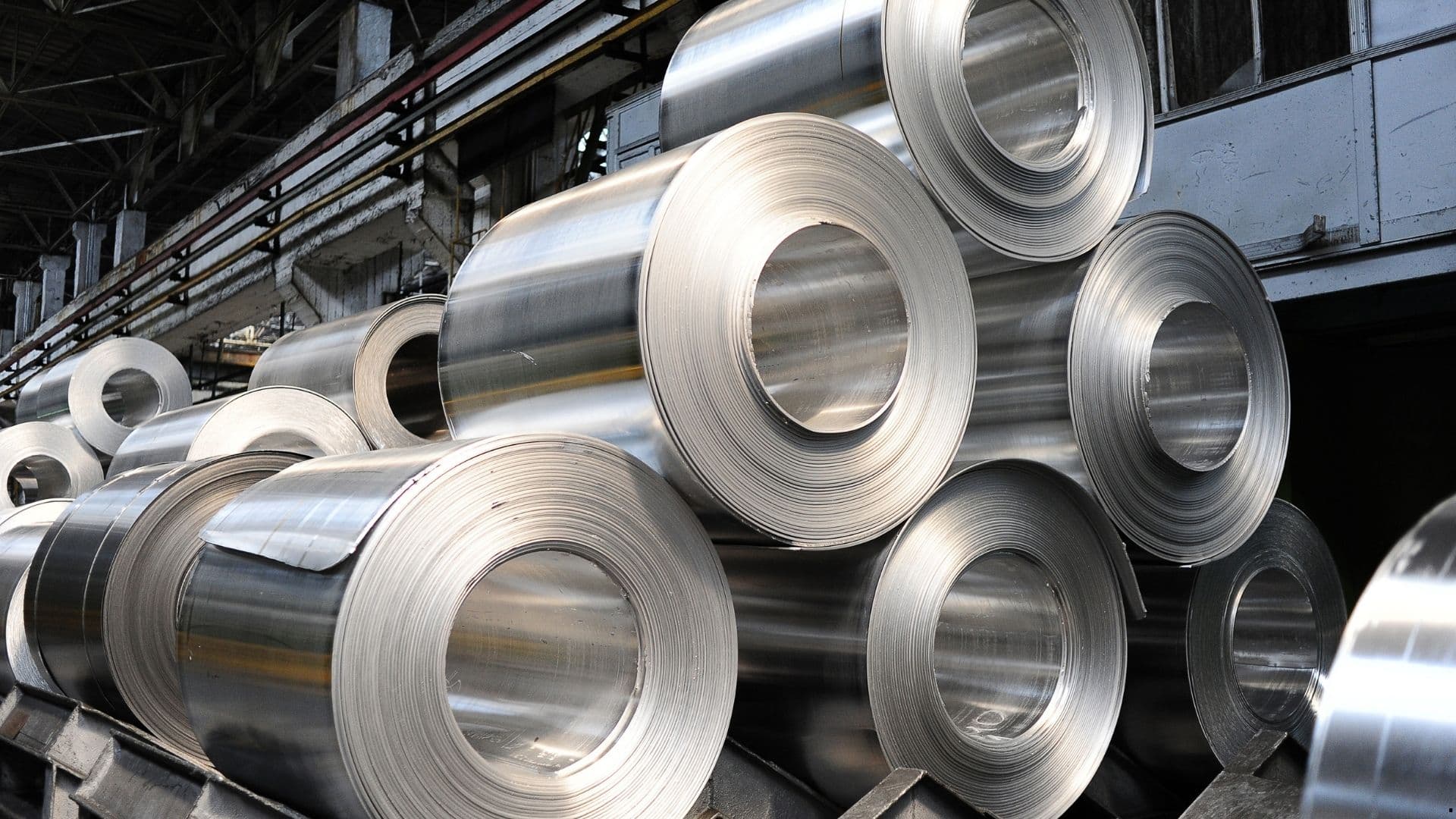 Rolled metal coils stacked in a mill.